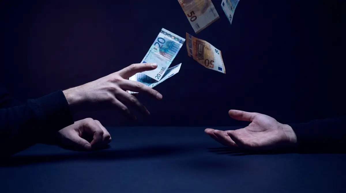 Euro banknotes flying away between two hands on a dark background: Meta Ads budget spent without generating conversions